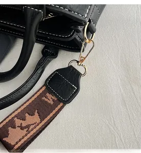 Detail of lychee grain leather tote with gold-tone hardware and jacquard strap