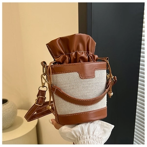 Close-up of canvas and leather bucket bag with drawstring and adjustable shoulder strap
