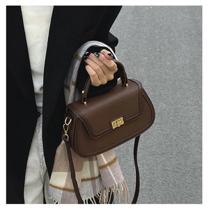 Gros plan d'un sac à main marron en cuir avec boucle dorée sur fond de rue urbaine