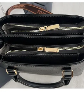 Detail of smooth gold double zippers and lychee grain faux leather on a black handbag