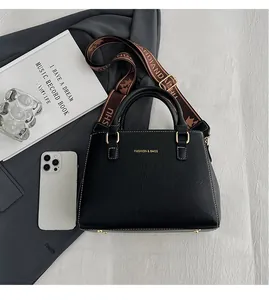 Detailed shot of black pebbled leather tote bag with gold hardware and jacquard strap