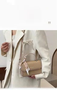 Close-up of khaki crossbody bag with a heart-patterned silk scarf on the handle