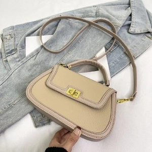 Détail du sac à main en cuir grainé avec fermoir rotatif doré sur fond en denim