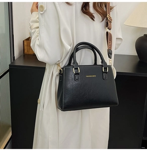 Detail of black leather tote bag with gold lettering and jacquard wide shoulder strap