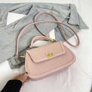 Détail du sac à main rose avec texture litchi et fermoir pivotant en métal doré chic