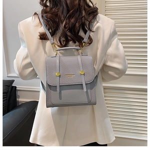 Détail du sac à dos en cuir gris-bleu avec texture tressée et boucles dorées sur mannequin