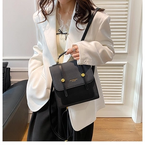 Détail du sac à main noir en cuir texturé avec boucles dorées et bandoulière élégante
