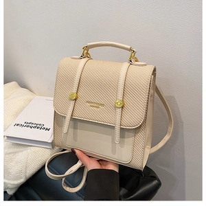 Détail d'un sac à dos en cuir crème avec texture tissée et détails dorés ronds