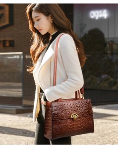 Detail of brown crocodile pattern leather handbag with elegant gold clasp and shoulder strap