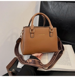 Close-up of caramel brown tote bag with litchi texture and wide woven shoulder strap