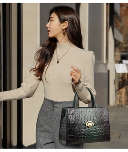 Detail of dark green crocodile texture leather bag with elegant golden clasp closure