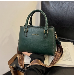 Detail of dark green tote bag with wide brown patterned strap and fashion lettering