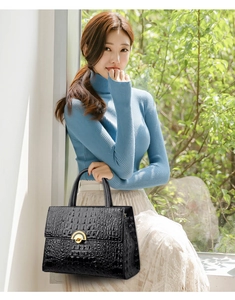 Detail of black crocodile texture handbag with gold metal clasp on a stylish shoulder bag