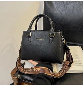 Close-up of black PU leather tote texture with fashion lettering and golden hardware