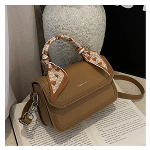 Detail of brown textured leather small square bag with decorative heart print silk scarf handle