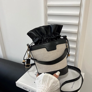 Chic two-tone bucket bag in cream fabric and black leather with drawstring closure