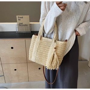Chic woven straw tote bag with fringe tassels and shoulder strap for beach holidays
