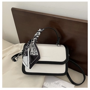 Detail of lychee leather crossbody bag with black contrast trim and silk scarf handle