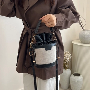 Retro canvas and black leather bucket bag with gold hardware and a drawstring closure