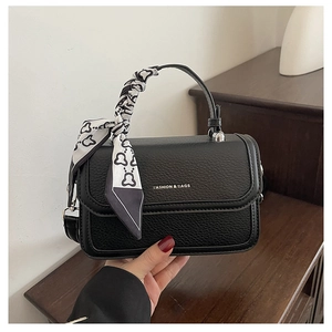Close-up of black lychee grain leather handbag with silk scarf wrapped on the handle