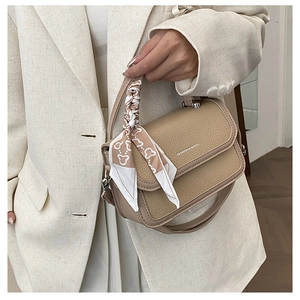 Detail of beige lychee leather handbag featuring a silk scarf wrapped handle and print