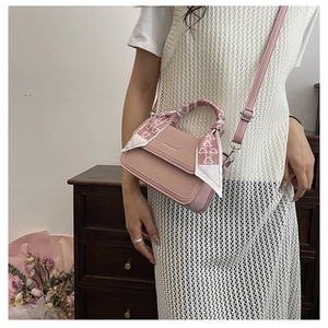 Pink litchi texture crossbody bag with silk scarf wrapped handle on a vintage background