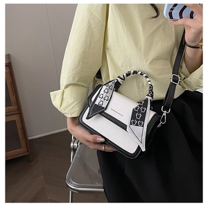 Detail of minimalist black and white crossbody bag with silk scarf handle and pebble texture
