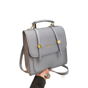 Sac à dos gris bi-matière avec texture tissée et boucle dorée vue de face minimaliste