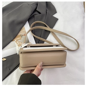 Detail view of structured two-tone crossbody bag with elegant heart pattern silk scarf