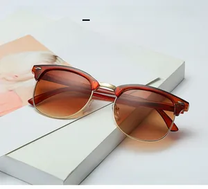Detailed view of tortoiseshell semi-rimless sunglasses with gold accents on white books