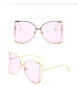 Détail de lunettes de soleil en métal doré avec verres roses et embouts en perles
