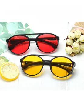 Red and yellow candy-colored retro round sunglasses with black frames on white wood