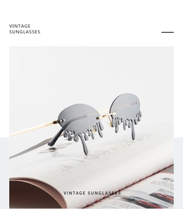 Detail of tear-shaped rimless sunglasses with gold metal frame on a magazine background