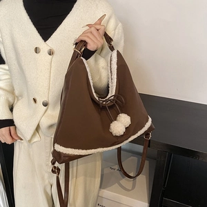 Détail du sac cabas en cuir marron foncé avec bordure en fausse fourrure blanche et pompons