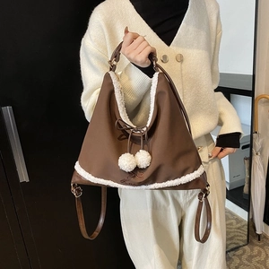 Détail d'un sac à dos en nylon marron avec bordure en fausse fourrure blanche et pompons