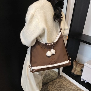 Vue détaillée du sac porté épaule en toile marron avec bordure en peluche et pompons