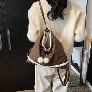 Détail du sac à main marron foncé avec bordure en similicuir blanc et pompons en peluche
