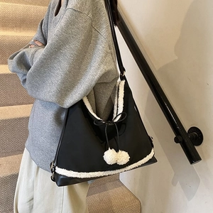 Détail du cabas en nylon noir avec bordure en polaire blanche et breloques pompons