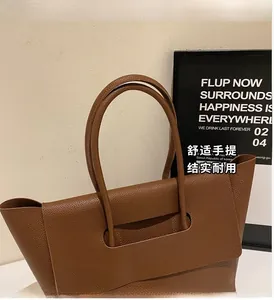 Détail du sac cabas en cuir marron à grain litchi avec ses poignées circulaires