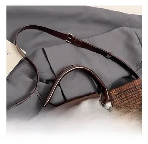Detail of brown quilted fabric tote with leather handles and adjustable shoulder strap