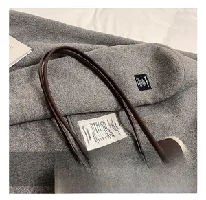 Detail shot of brown leather bag with soft white shearling trim and slim handles
