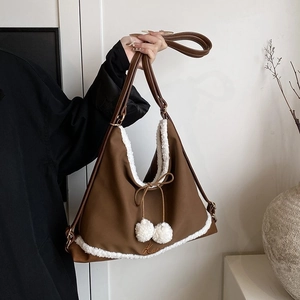 Détail du sac bandoulière marron avec bordure en fausse fourrure blanche et pompons doux