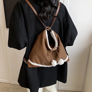 Sac à dos en toile marron avec bordure en fausse fourrure blanche porté par un mannequin