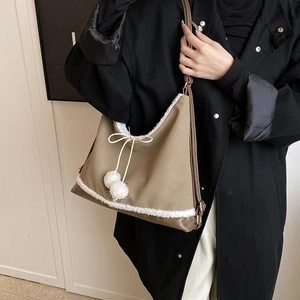 Détail du sac à bandoulière en nylon kaki avec bordure en peluche blanche et pompons