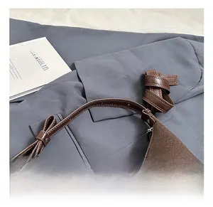 Dettaglio di borsa in feltro marrone con manico in pelle e nodo a fiocco molto elegante