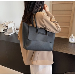 Grand sac cabas noir en cuir grainé porté par un mannequin en tenue de bureau