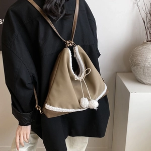 Détail du sac à dos triangle kaki avec bordure en fausse fourrure blanche et pompons