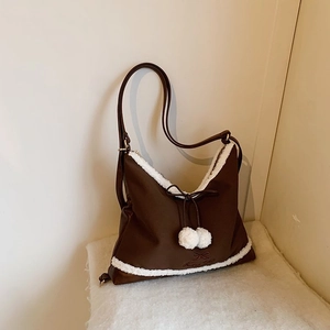 Détail du sac en similicuir marron foncé avec bordure en molleton blanc et nœud à pompons