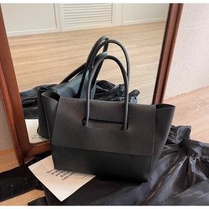 Gros plan d'un sac cabas en cuir grainé noir avec une structure de poignée intégrée