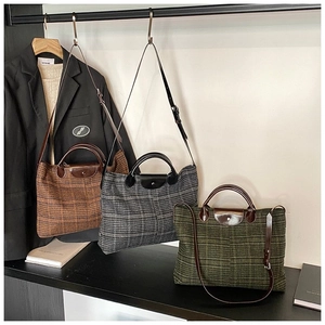 Three plaid tote bags in brown, grey and green displayed with professional attire